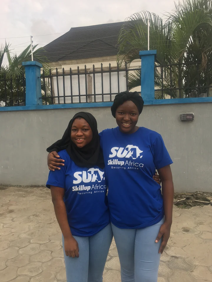 Two smiling women wearing SkillUp Africa shirts