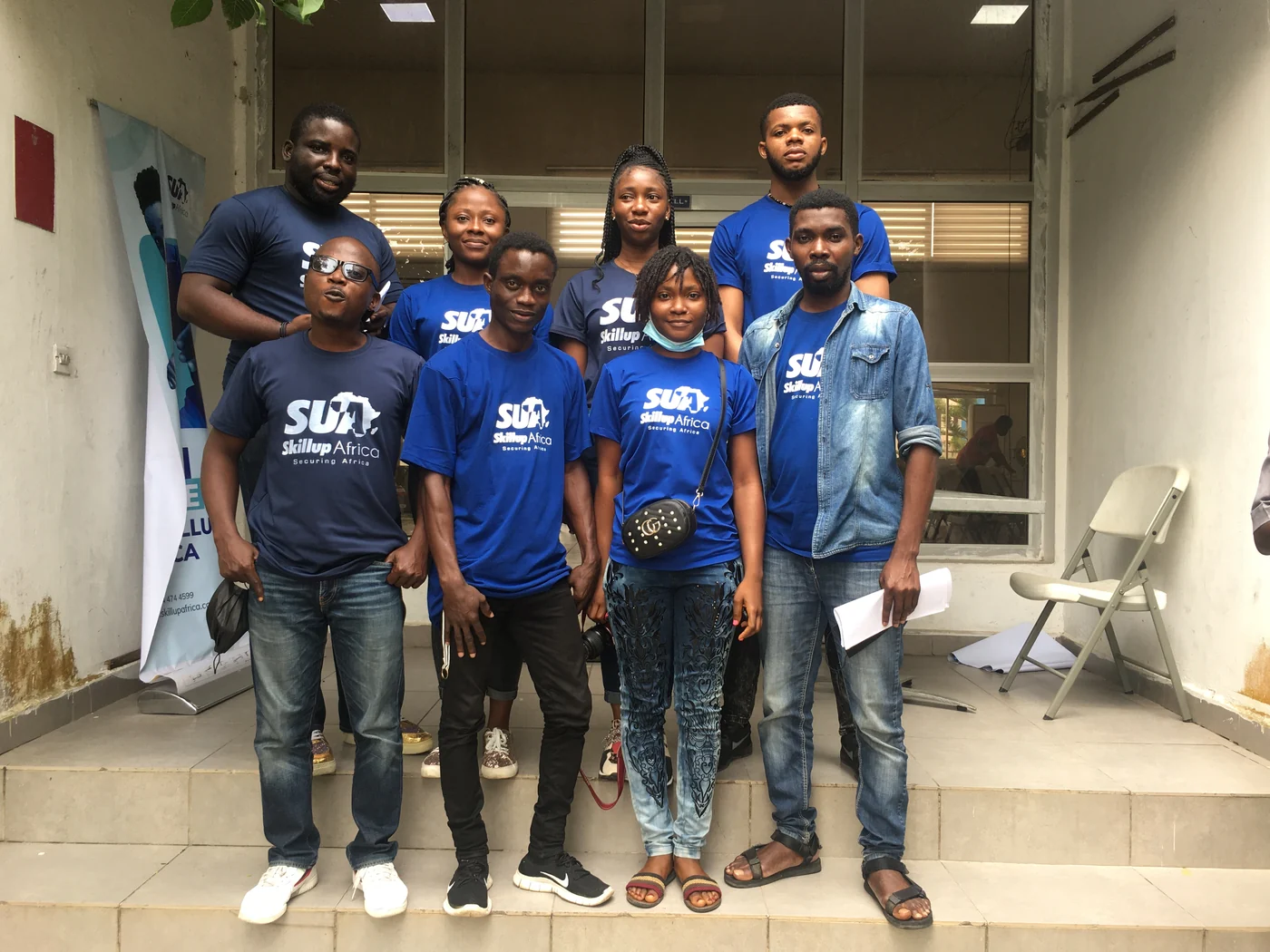 A SkillUp Africa group gathered on steps, with several people wearing blue community shirts