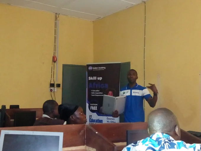 A SkillUp Africa facilitator addressing learners beside a programme banner