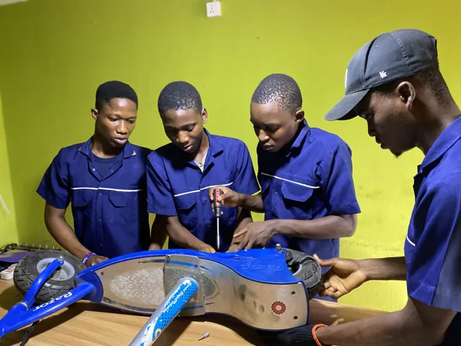 SkillUp Africa Garage learners working together on a scooter during practical electronics training