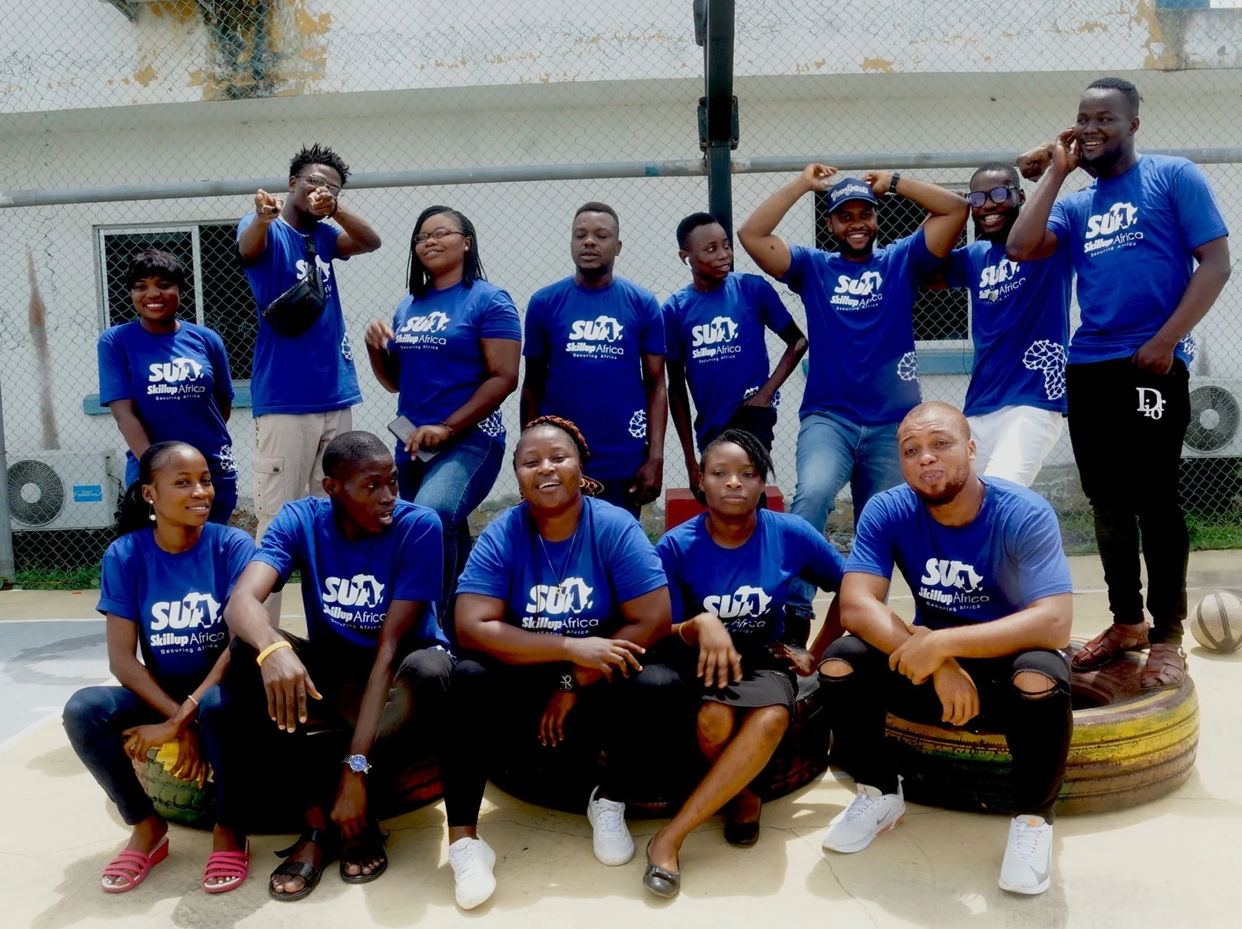 A joyful group wearing SkillUp Africa T-shirts, gathered together outside
